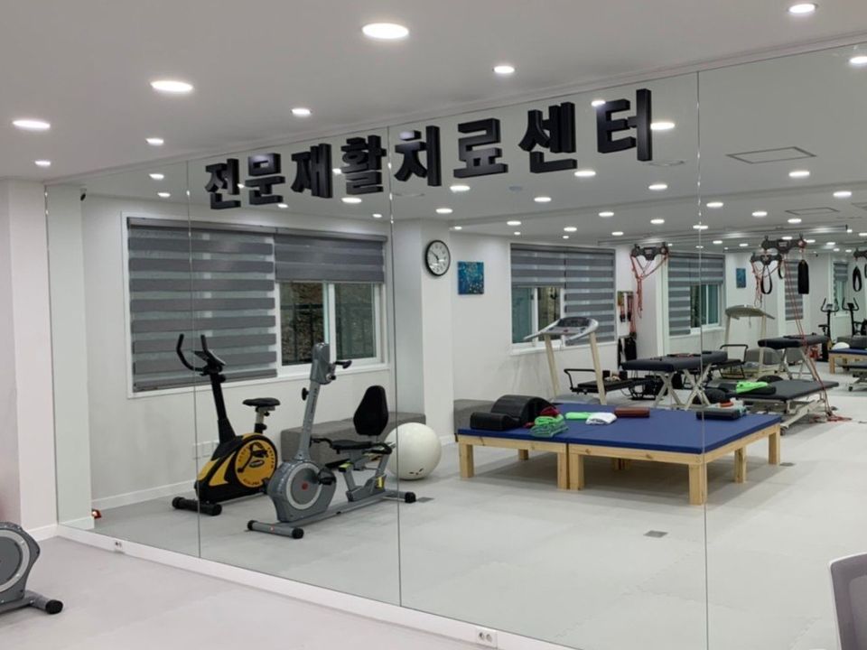 거울 벽과 운동 기구가 있는 전문재활치료 센터 내부